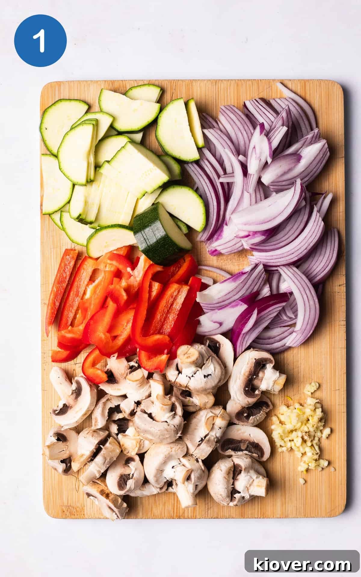 red onion, pepper, courgette, and mushrooms on a wooden cutting board.