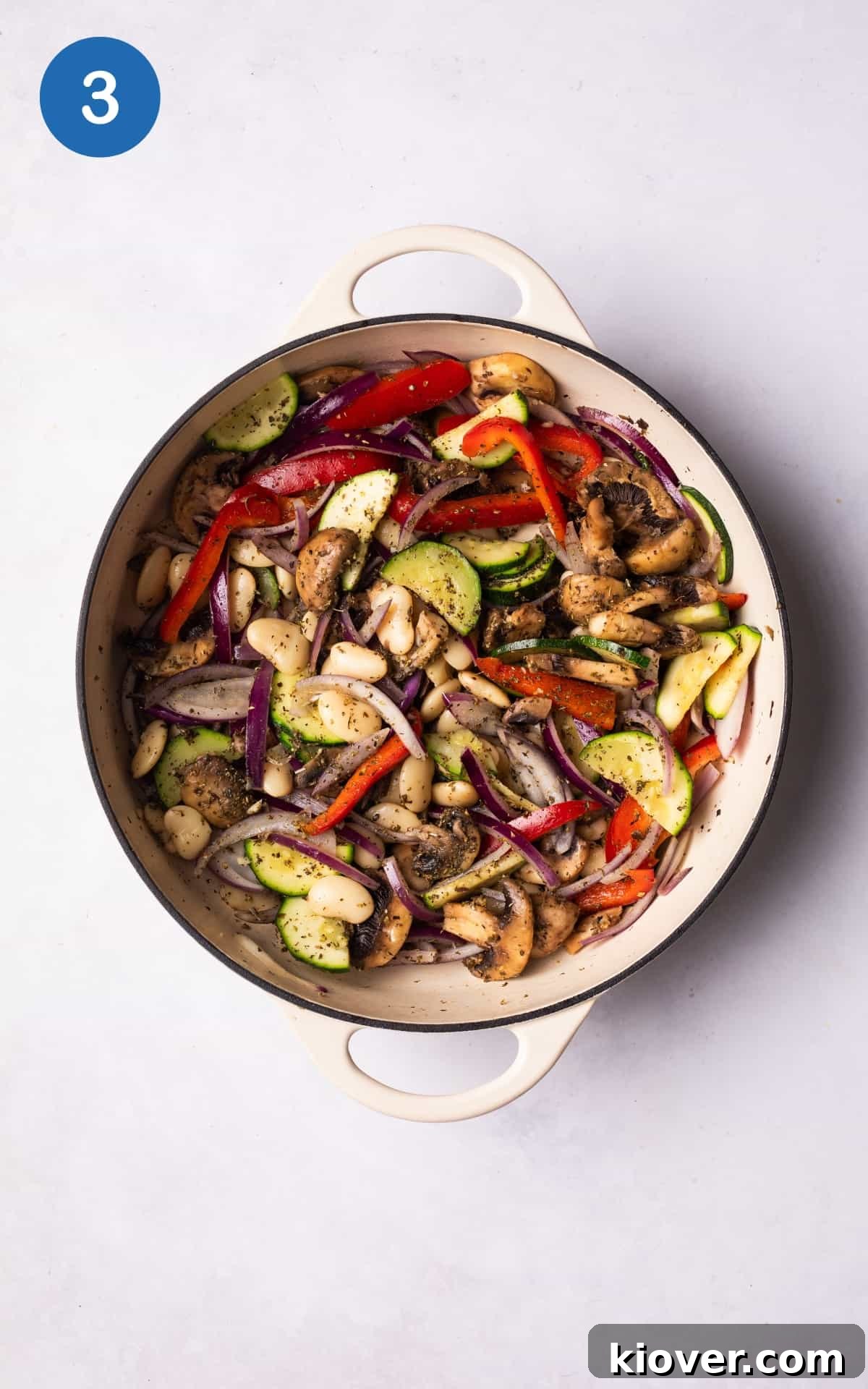 adding crushed garlic, dried oregano, basil, and butterbeans to the pot with vegetables.