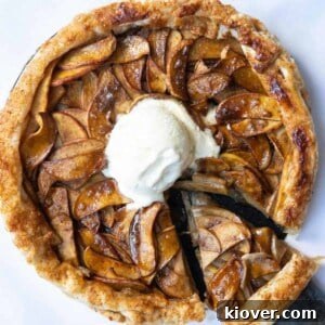 A circular puff pastry apple tart, with a scoop of ice cream in the center, and a slice already removed.
