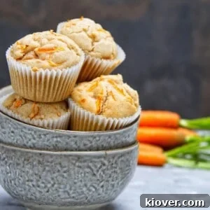 Delicious vegan carrot cake cupcakes in a bowl, with fresh carrots in the background.