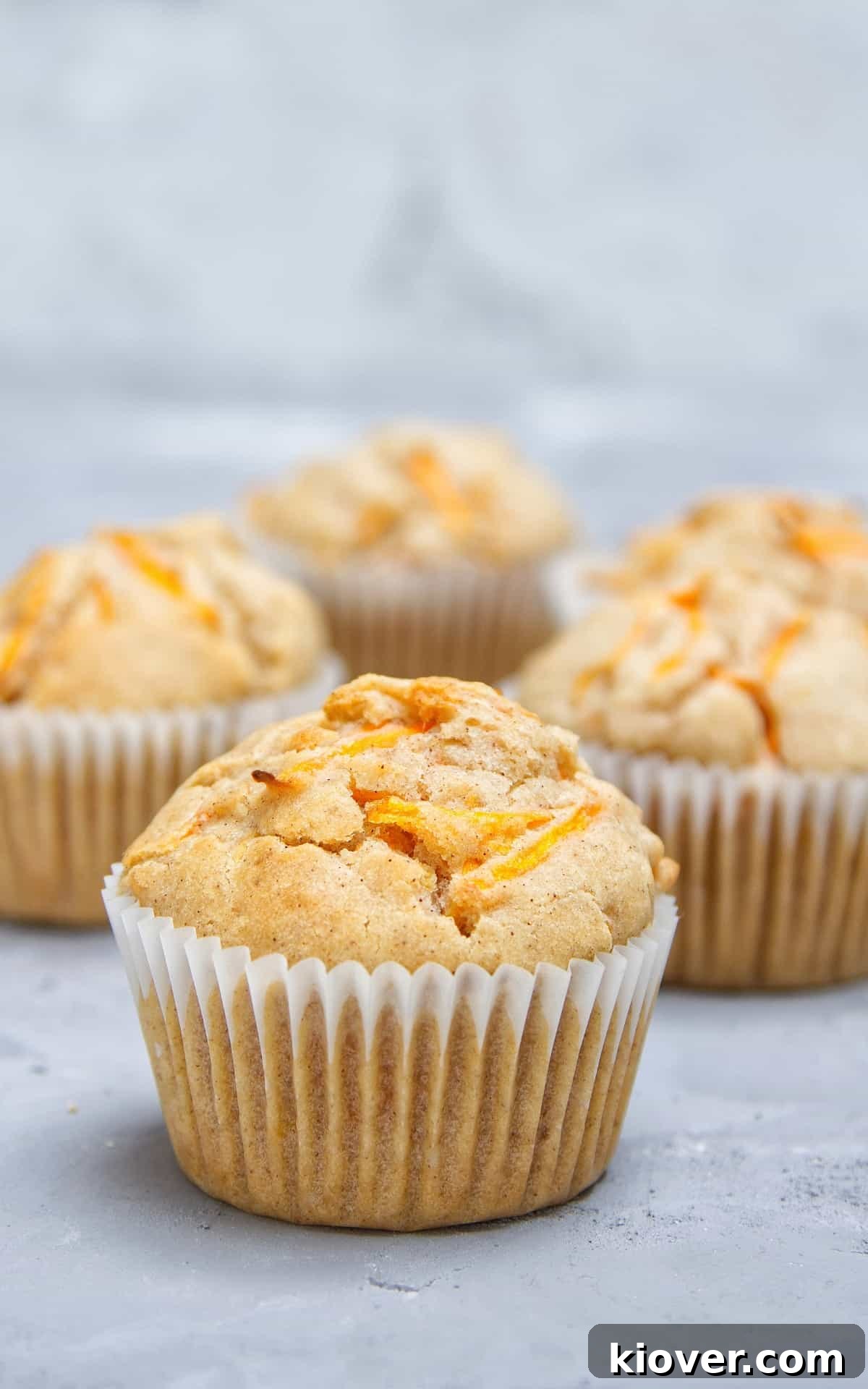 A close-up shot of perfectly baked Vegan Carrot Cake Cupcakes presented in charming muffin baskets, highlighting their fluffy texture and golden-brown tops.