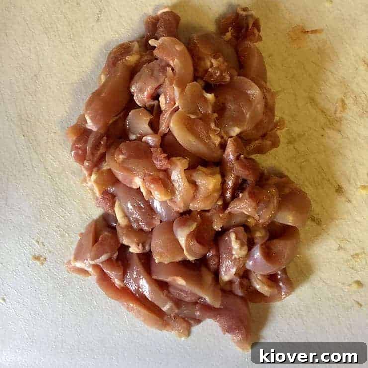 Neatly cut chicken thighs arranged on a wooden cutting board, showcasing their readiness for a stir-fry.
