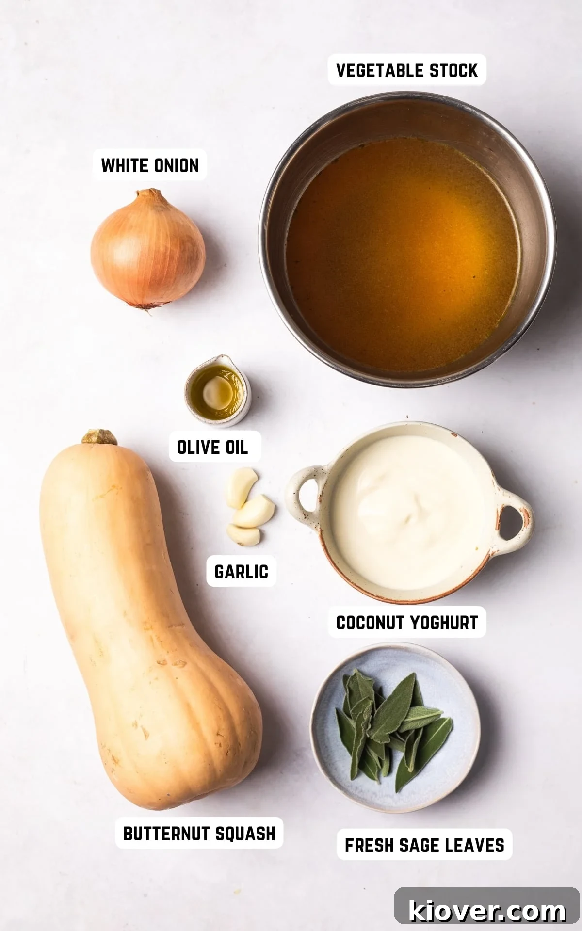 Autumn Squash Comfort 3 A selection of fresh ingredients laid out on a wooden board, including a whole butternut squash, onions, garlic, sage, and a bottle of olive oil, ready to make butternut squash soup.