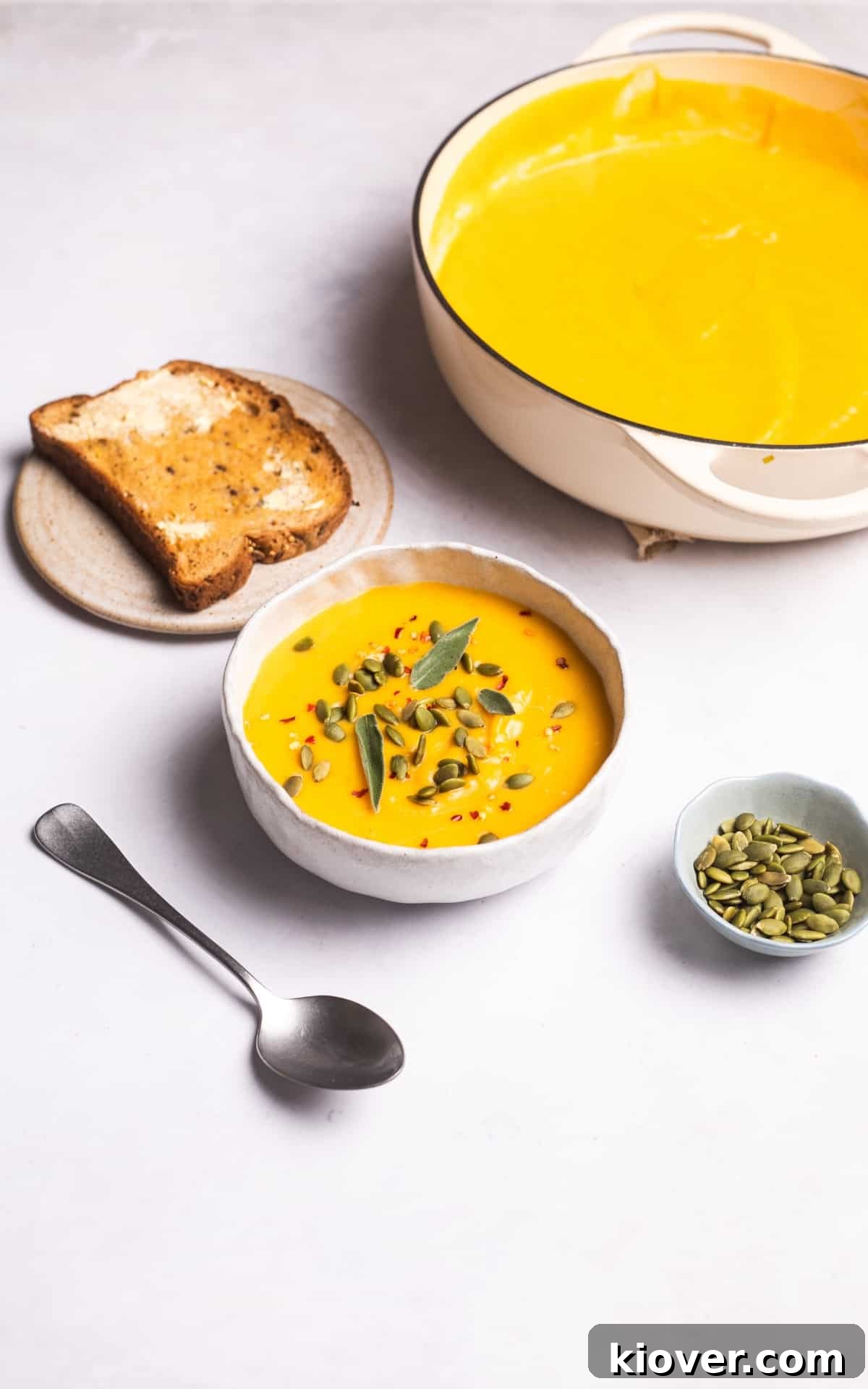 Autumn Squash Comfort 9 Rich, orange butternut squash soup garnished generously with fresh sage leaves, bright green pumpkin seeds, and a sprinkle of red chili flakes.