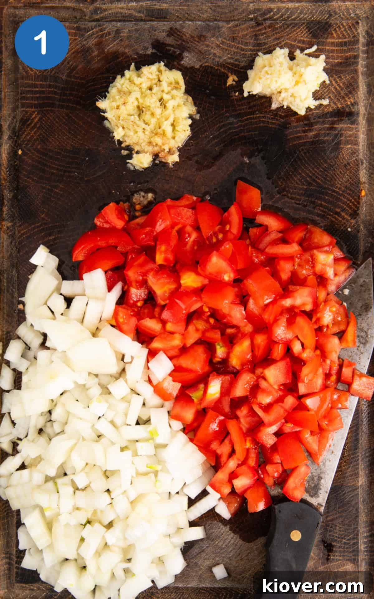 onion, garlic, ginger and tomatoes on a cutting board.