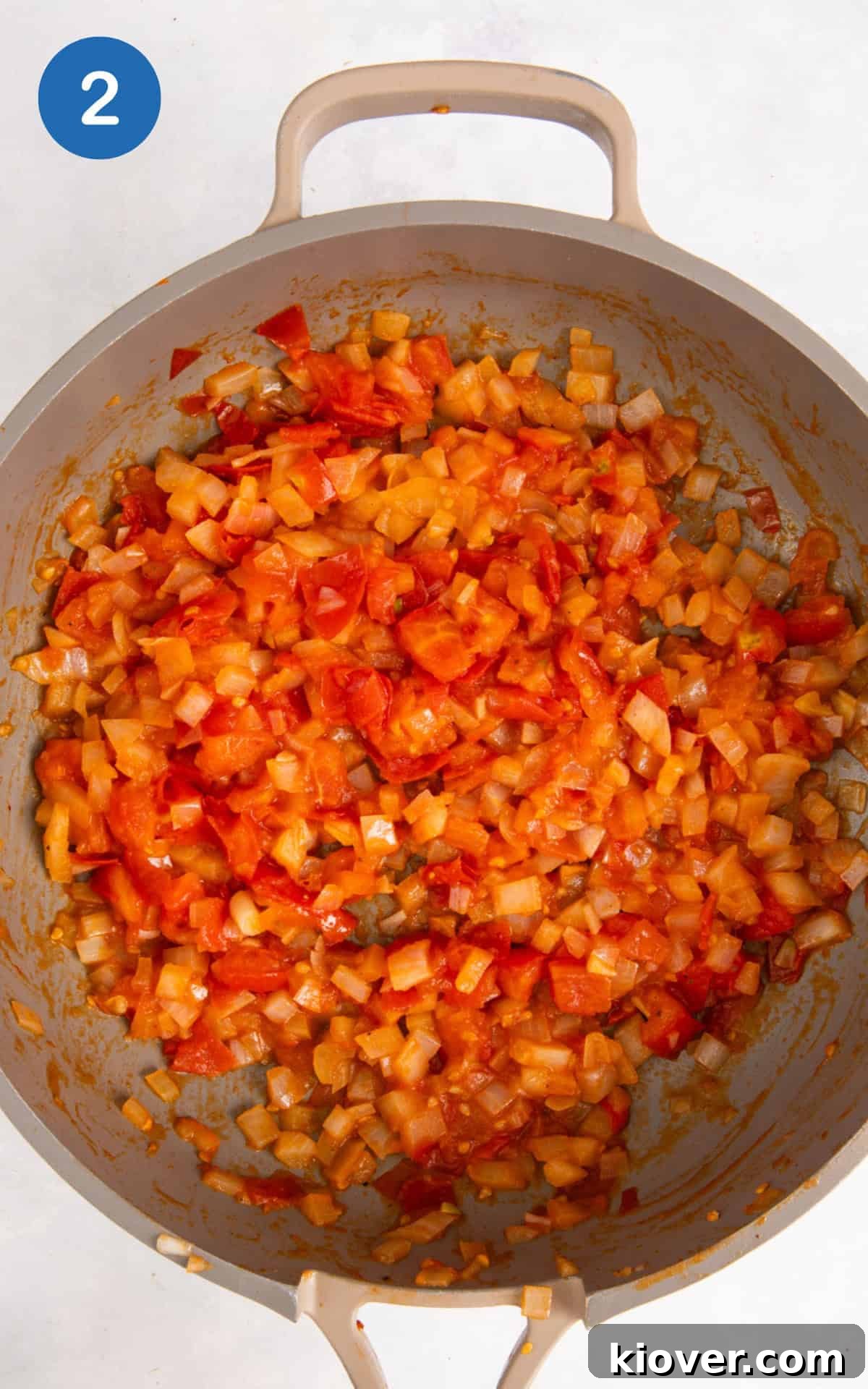 frying onion and tomatoes with salt and pepper in a pan.