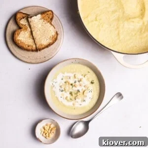 A vibrant bowl of creamy celeriac soup, elegantly garnished with a swirl of cream and crunchy crushed hazelnuts, signifying a delightful and healthy meal.