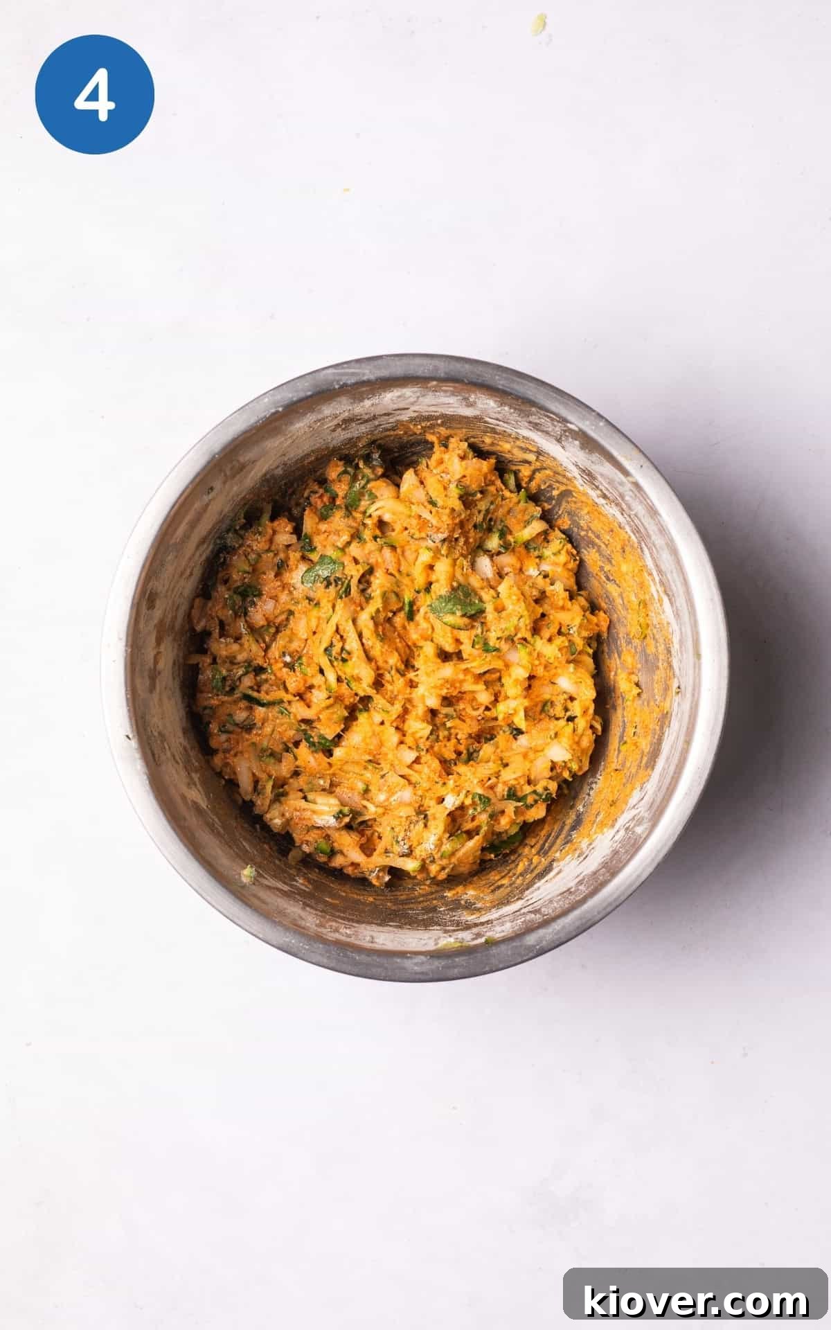 Crispy Zucchini Fritters 7 Combined mixture of courgette, onion, garlic, parsley, gram flour, paprika, salt, and baking powder in a bowl.