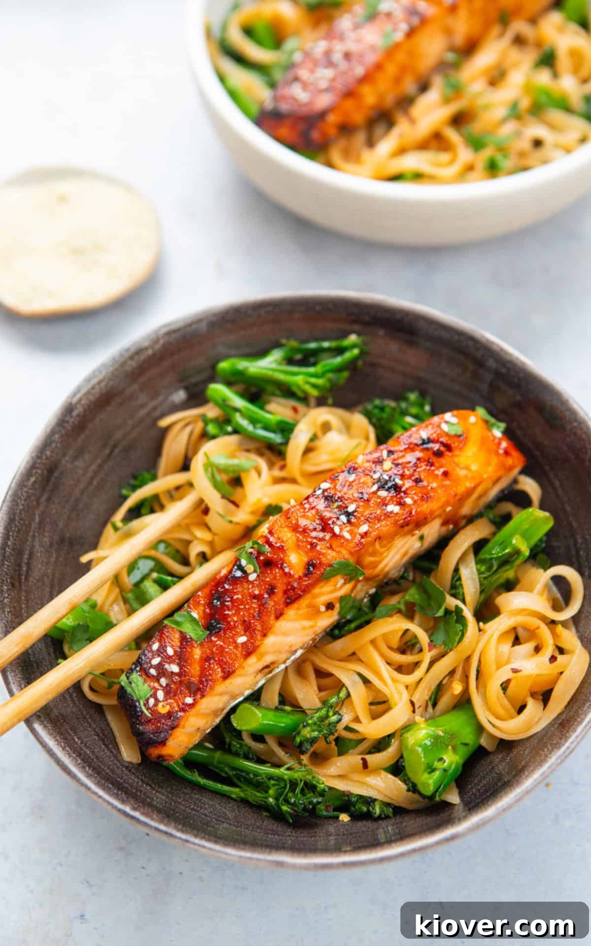 Plated Teriyaki Salmon Noodles with broccoli, sesame seeds, and parsley.