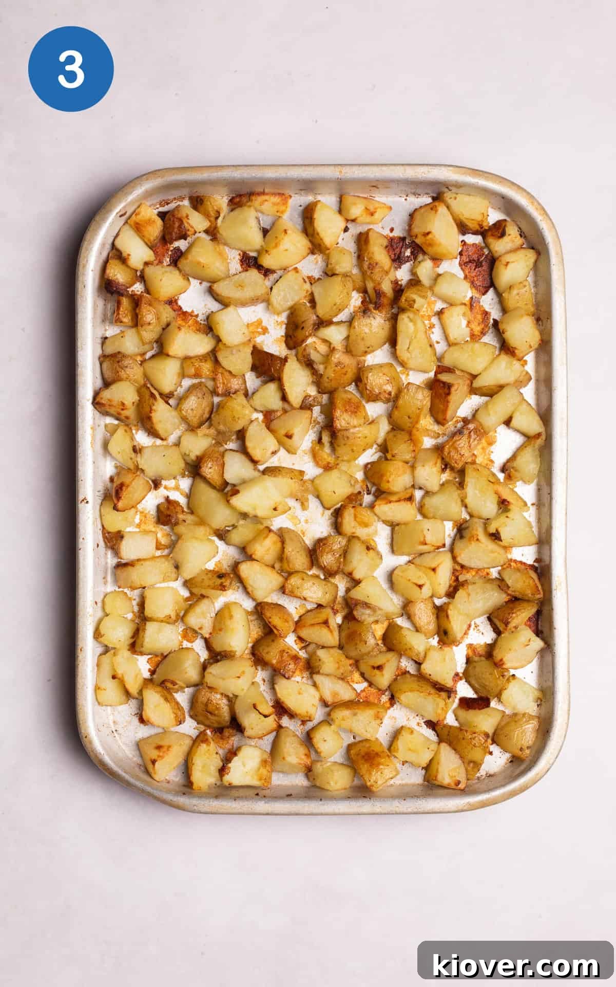 Golden Roasted Potato Cubes 6 Chopped white potatoes roasting in a baking pan, partially golden and ready for stirring.
