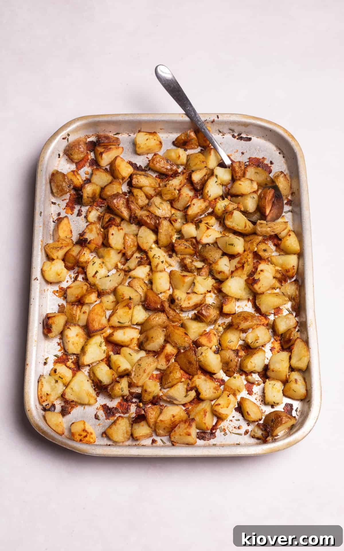 Golden Roasted Potato Cubes 8 A bowl of crispy Parmentier potatoes made in the oven, garnished with fresh herbs.