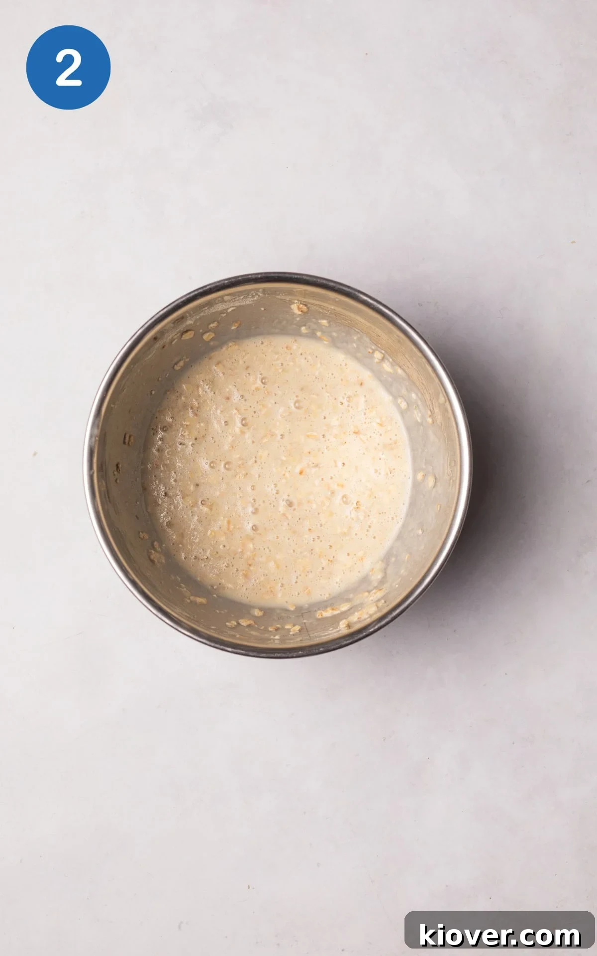 Protein powder, baking powder, milk, and oats being combined with mashed banana in a bowl.