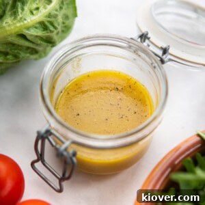 A glass jar filled with golden Maple Dijon Dressing, ready to be poured over a fresh salad.