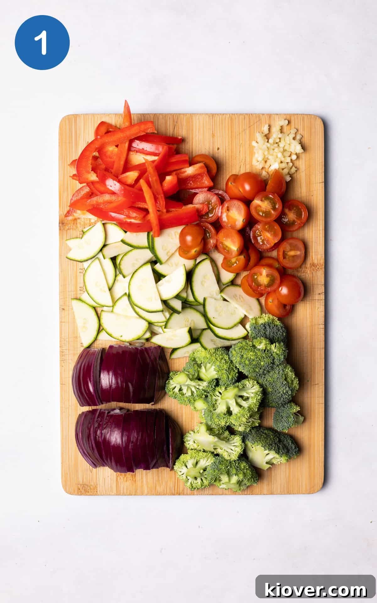 Hearty Sausage & Pasta Casserole 4 Fresh vegetables, including red onion, bell pepper, broccoli, courgette, and cherry tomatoes, neatly arranged on a wooden cutting board, ready for preparation.