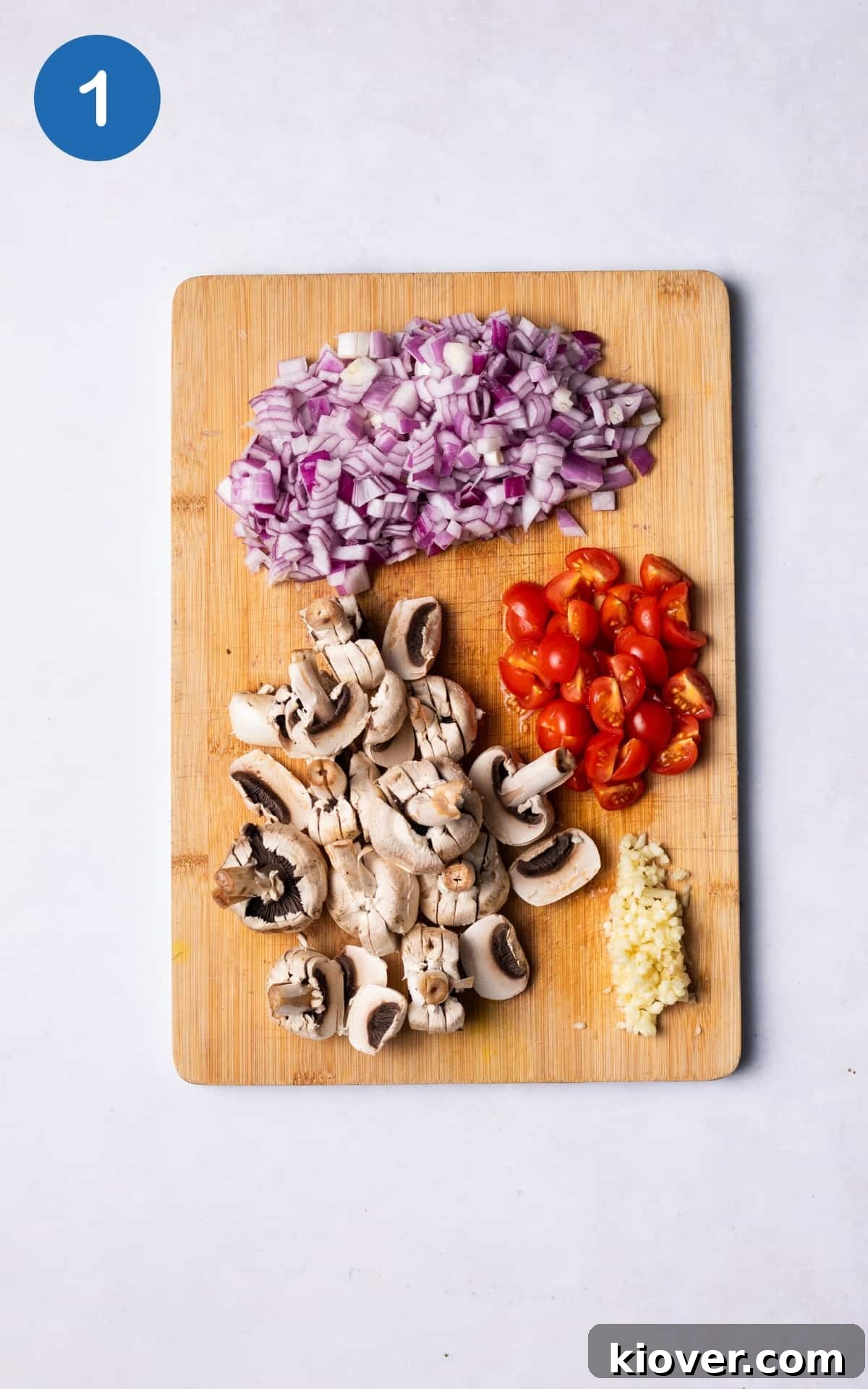 Plant-Based Moussaka Perfection 4 Diced onions, crushed garlic, chopped tomatoes, and sliced mushrooms neatly arranged on a cutting board, prepared for the sauce.