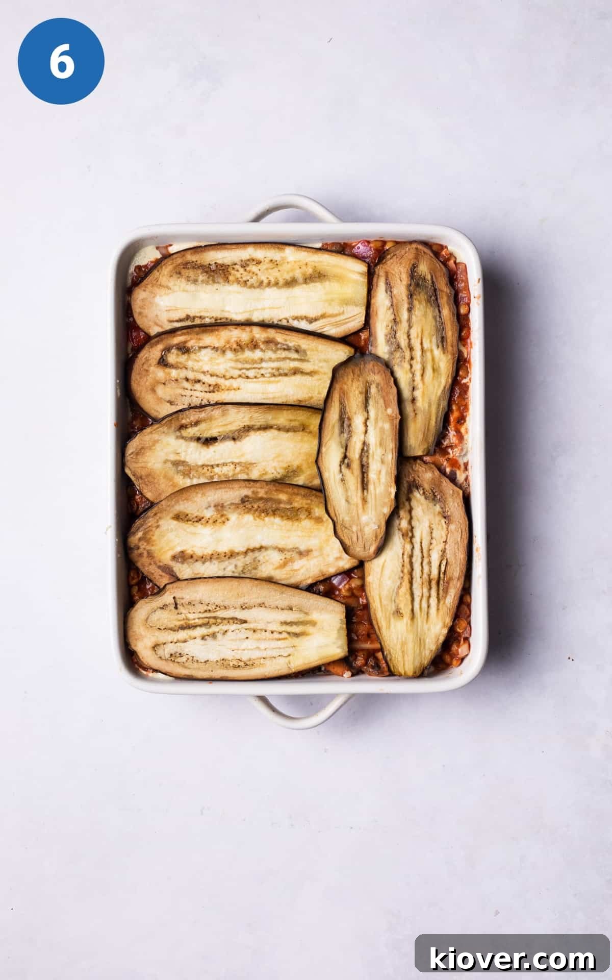 Plant-Based Moussaka Perfection 9 Layers of roasted aubergine, rich tomato lentil sauce, and creamy vegan white sauce meticulously arranged in a baking dish, resembling a lasagna.