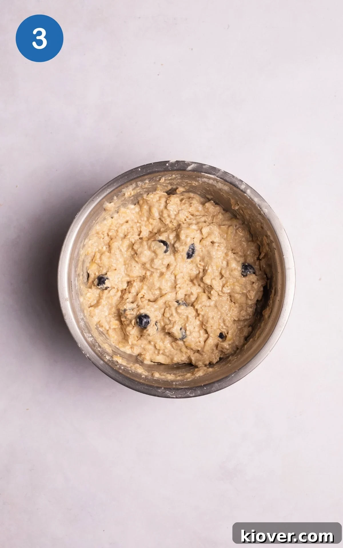 Adding oat flour, remaining oats, baking powder, and protein powder to the wet mixture in a bowl.