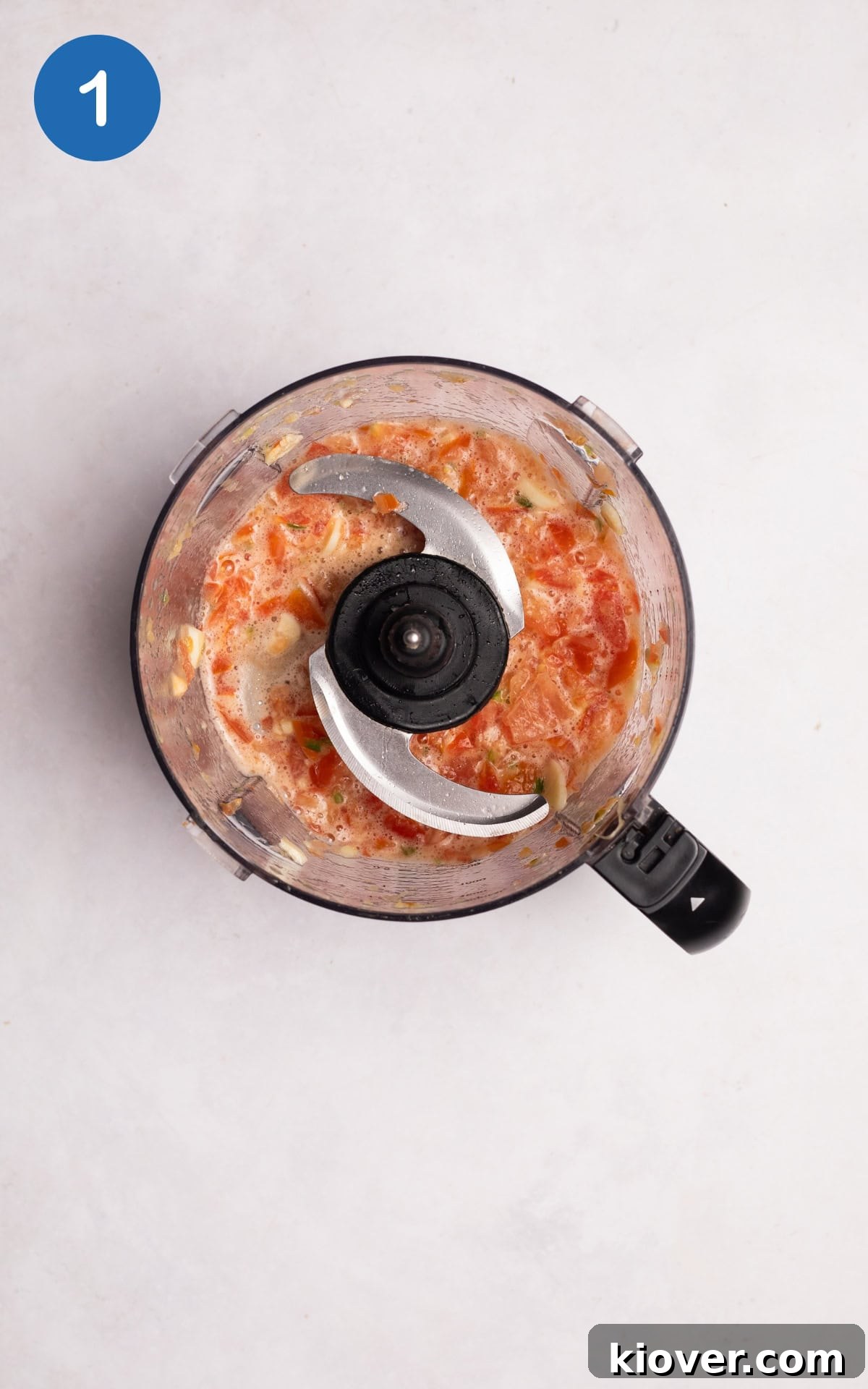 Blending garlic, ginger, green chilli and tomatoes in a food processor.