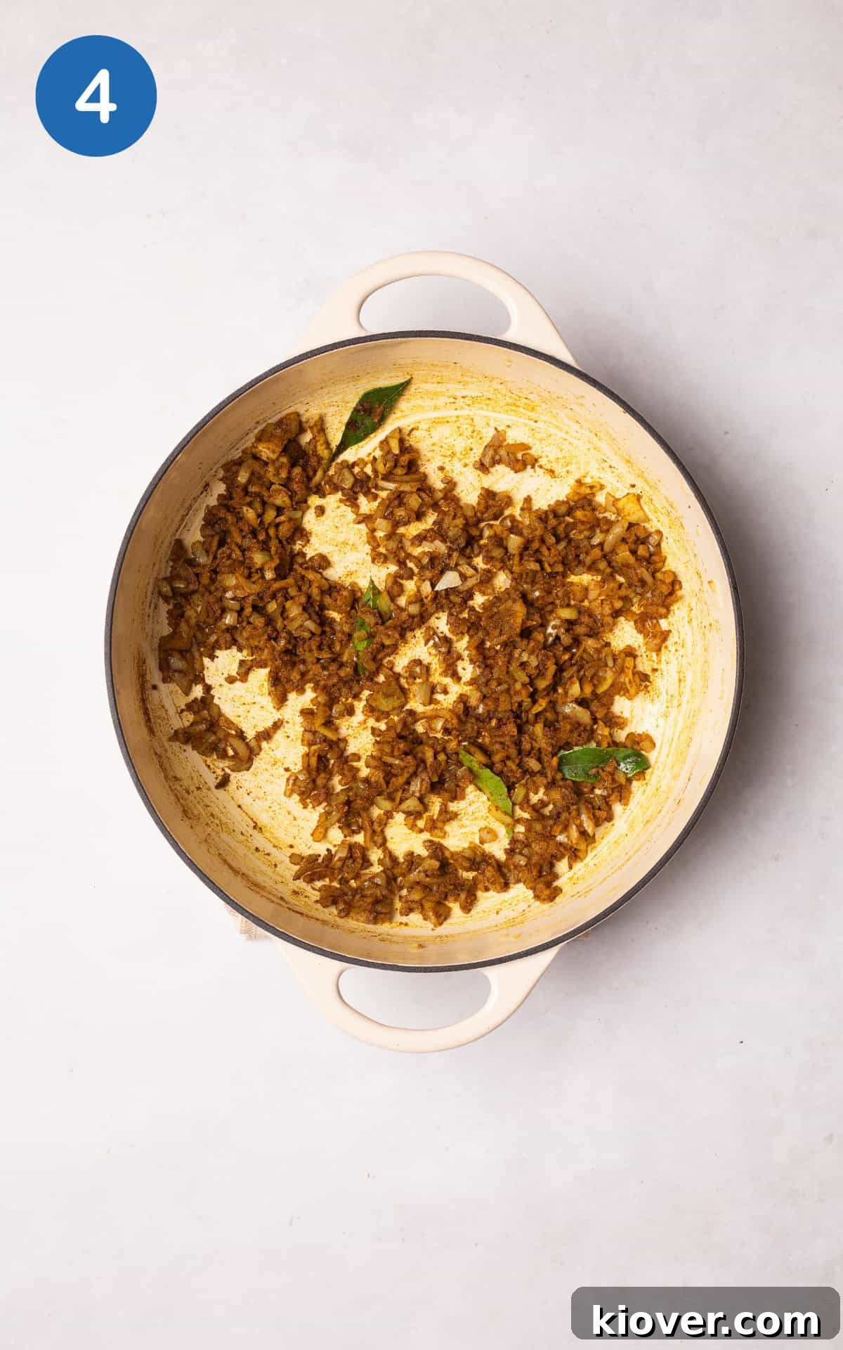 Mixing diced onion with spices, curry leaves, and salt.