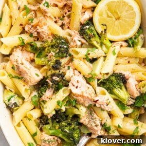 creamy salmon and broccoli pasta, garnished with fresh herbs.