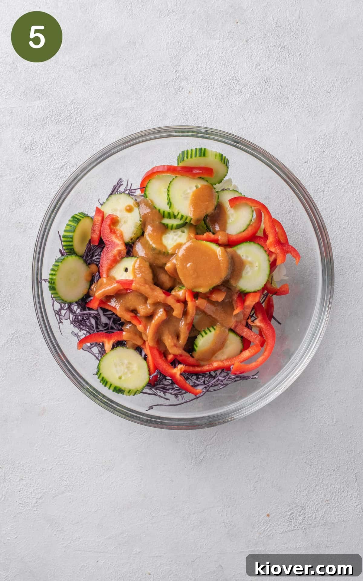A vibrant mix of shredded cabbage, crisp lettuce, and sliced red pepper ready to be dressed in a large bowl.