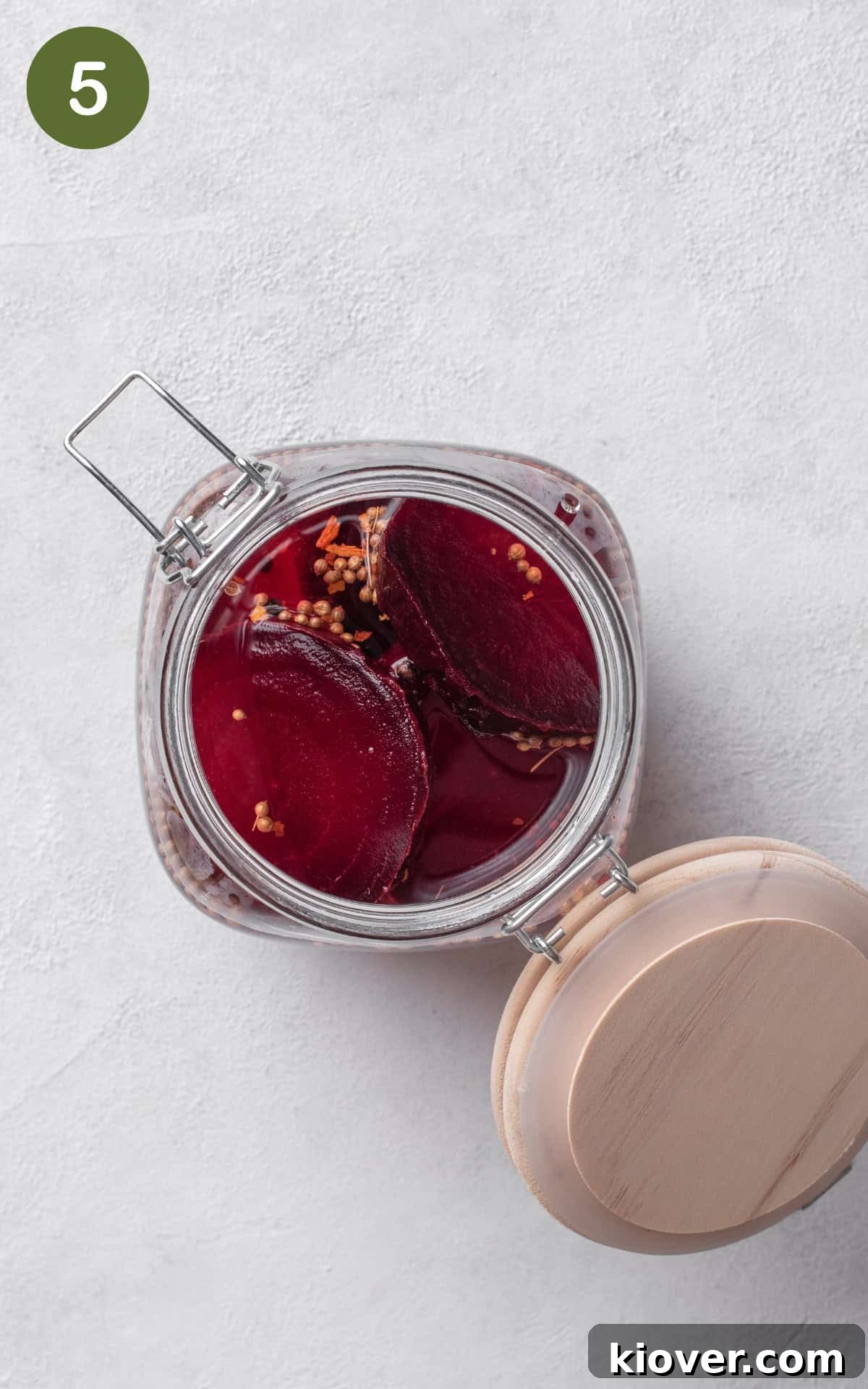 Sliced beets submerged in the freshly poured pickling brine inside a glass jar.