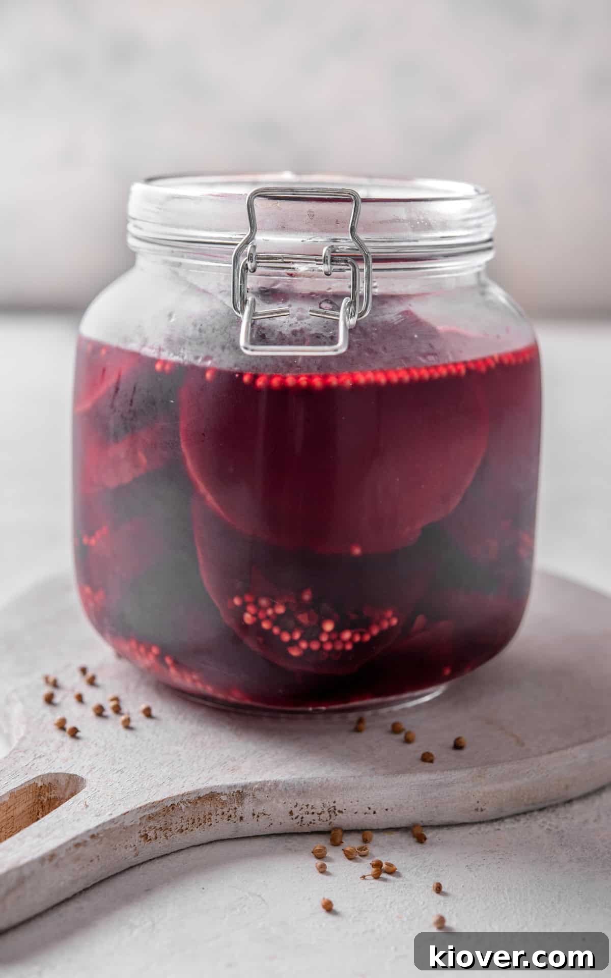 A glass jar filled with beautiful, ruby-red pickled beetroot slices, showcasing their vibrant color and readiness for serving.