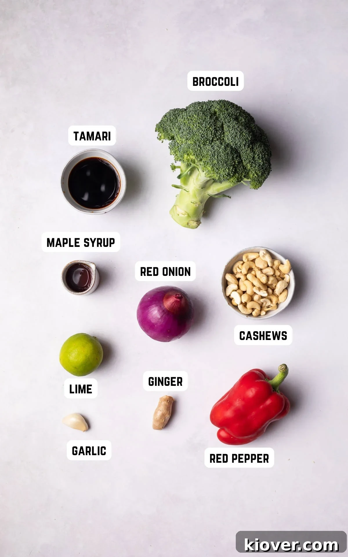 Fresh ingredients laid out for making Broccoli Stir Fry, including broccoli, bell pepper, tamari, maple syrup, lime, red onion, garlic, ginger, and cashews.
