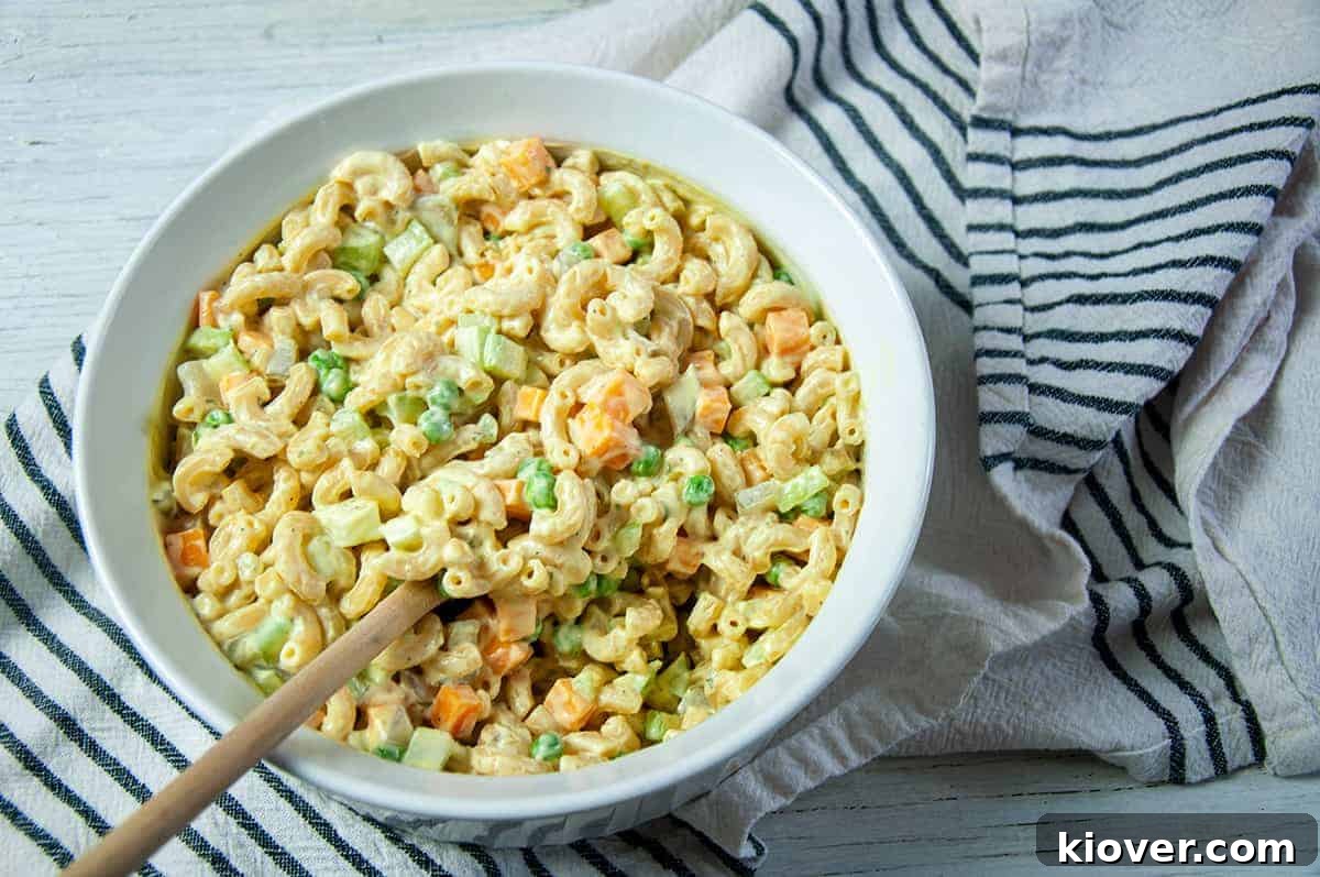 Overhead Shot with Chives Rancharoni Macaroni in a dish, but on a white and blue towel with a wooden spoon in the bowl.