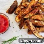 A plate of grilled jo jos with a small bowl of ketchup and some chives. All of this is on some parchment paper.