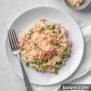 A creamy salmon risotto with green peas, served on a white plate, ready to be enjoyed.