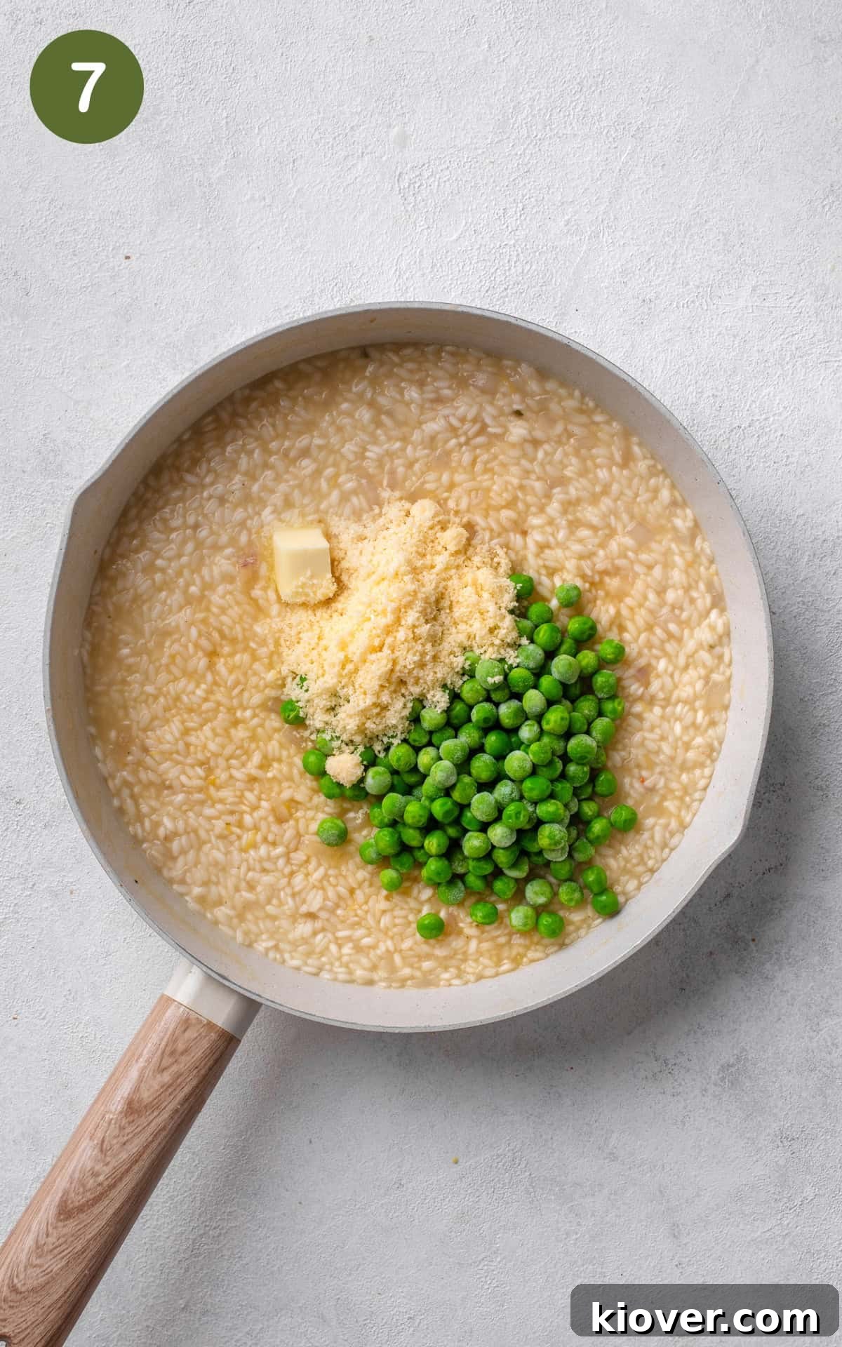 Frozen peas, butter, and grated Parmesan cheese being stirred into the creamy risotto.