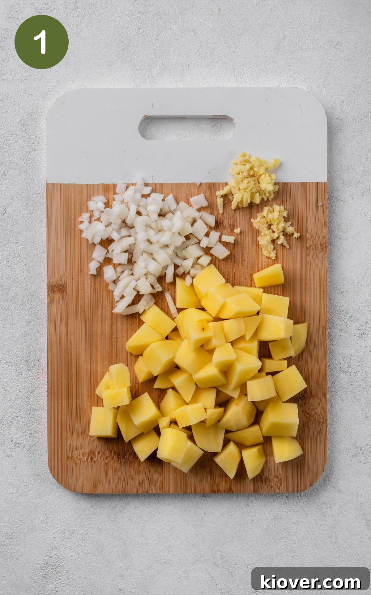Golden Potato Curry 4 Chopped white onion, minced garlic, and cubed potatoes on a wooden cutting board, ready for cooking.