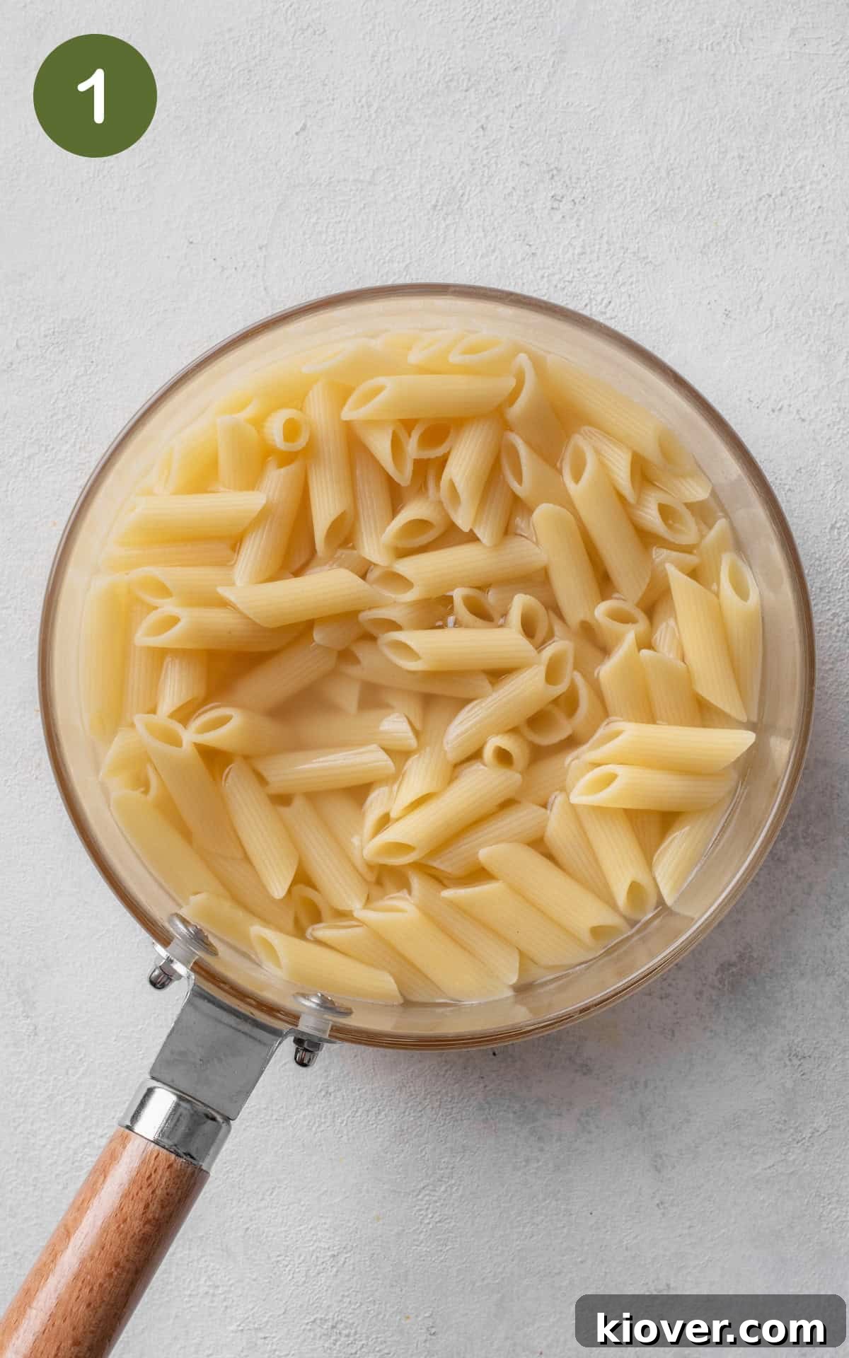 Penne pasta boiling in a large pot of salted water on a stove.