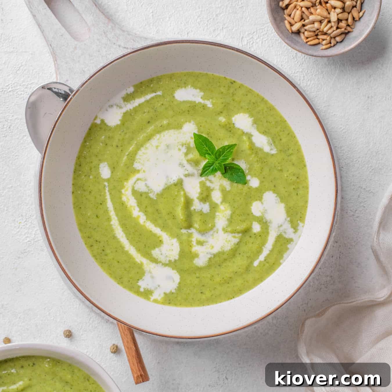A bowl of creamy broccoli soup garnished with fresh herbs, ready to be served.