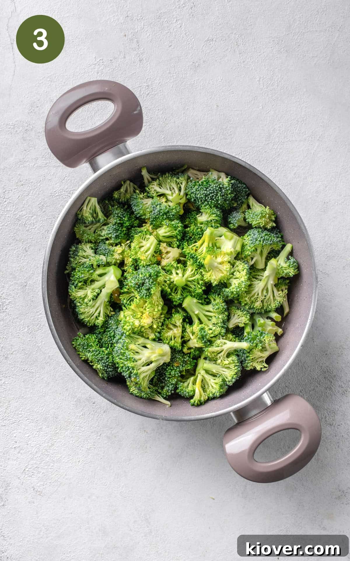 Broccoli florets and stalks, along with vegetable stock, simmering in a pot with other vegetables.