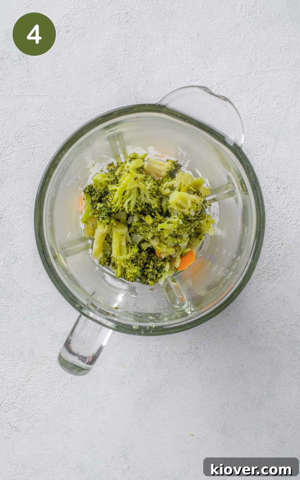 Cooked vegetables and liquid being transferred from the pot into a blender for pureeing.