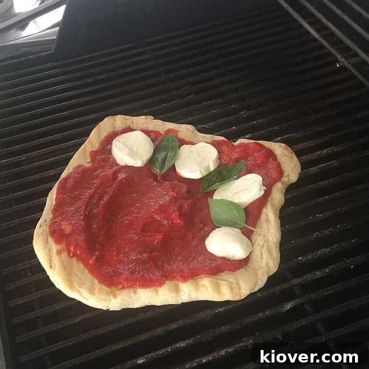 Ingredients on Grill After pizza dough has been flipped twice and sauce has been put on, with cheese and basil to follow.