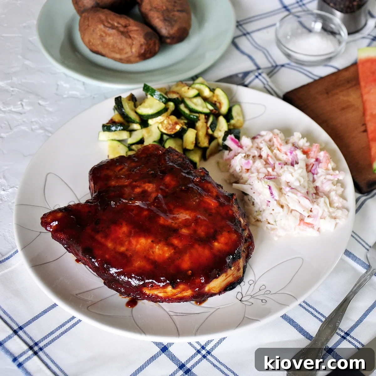 A perfectly grilled thick pork chop served with vibrant coleslaw and tender zucchini on a plate, ready to enjoy.