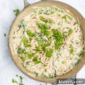 Creamy vegan spaghetti carbonara in a large frying pan topped with freshly chopped parsley