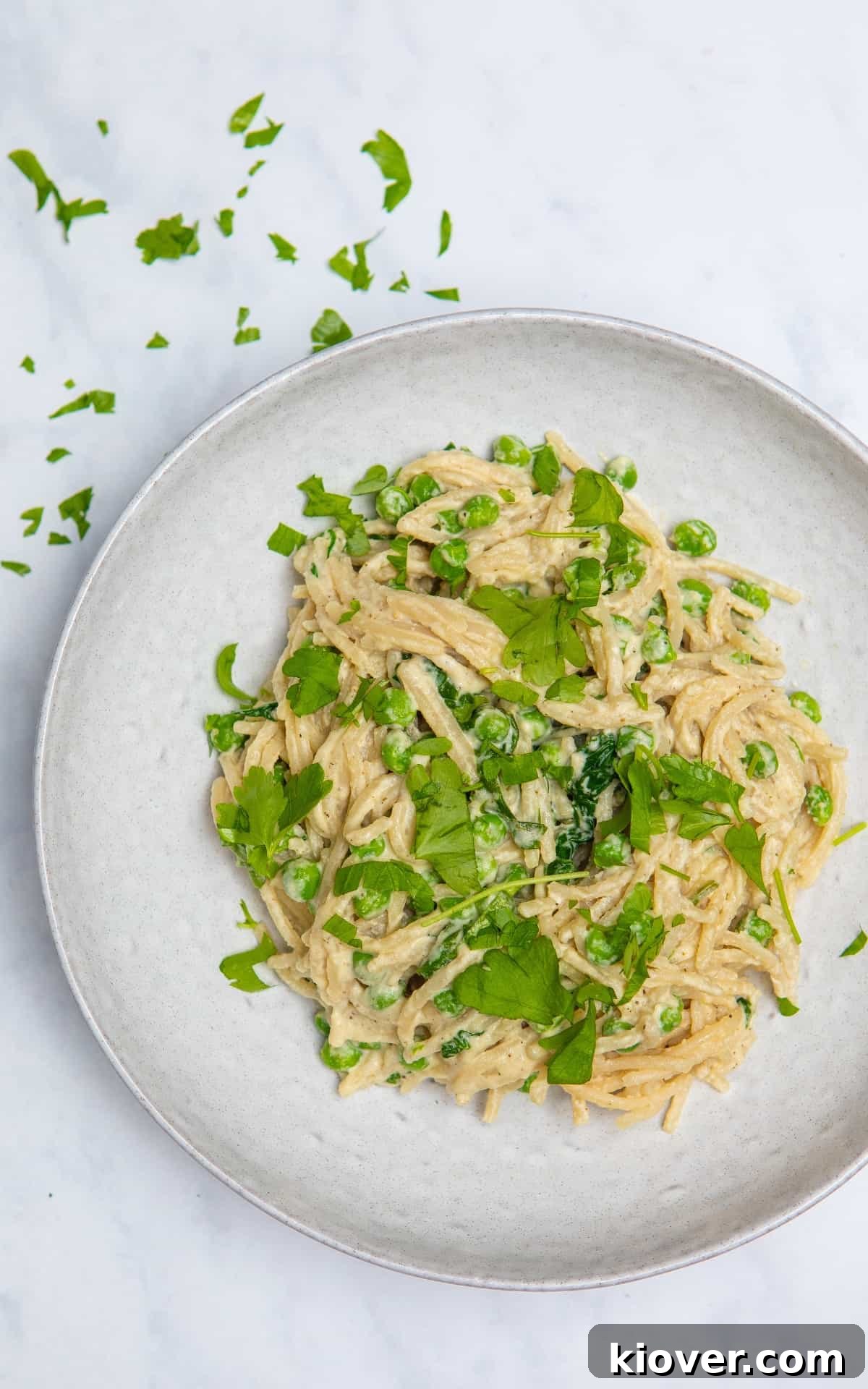 Vegan spaghetti carbonara on a grey plate, topped with freshly chopped coriander (or parsley).