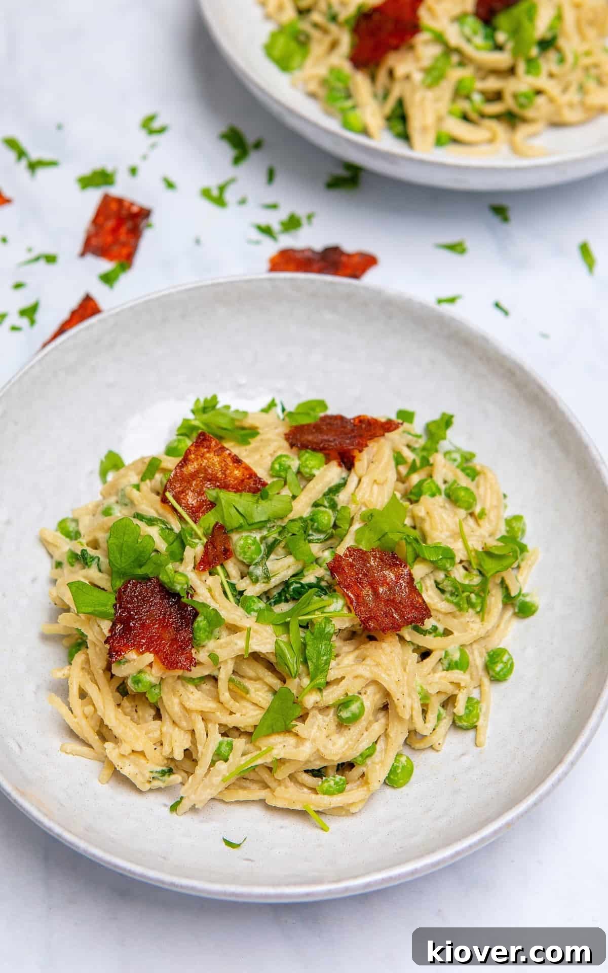 Crispy rice paper bacon generously placed on top of a serving of creamy vegan carbonara.