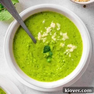 A beautiful bowl of green pea and mint soup, garnished with fresh mint.