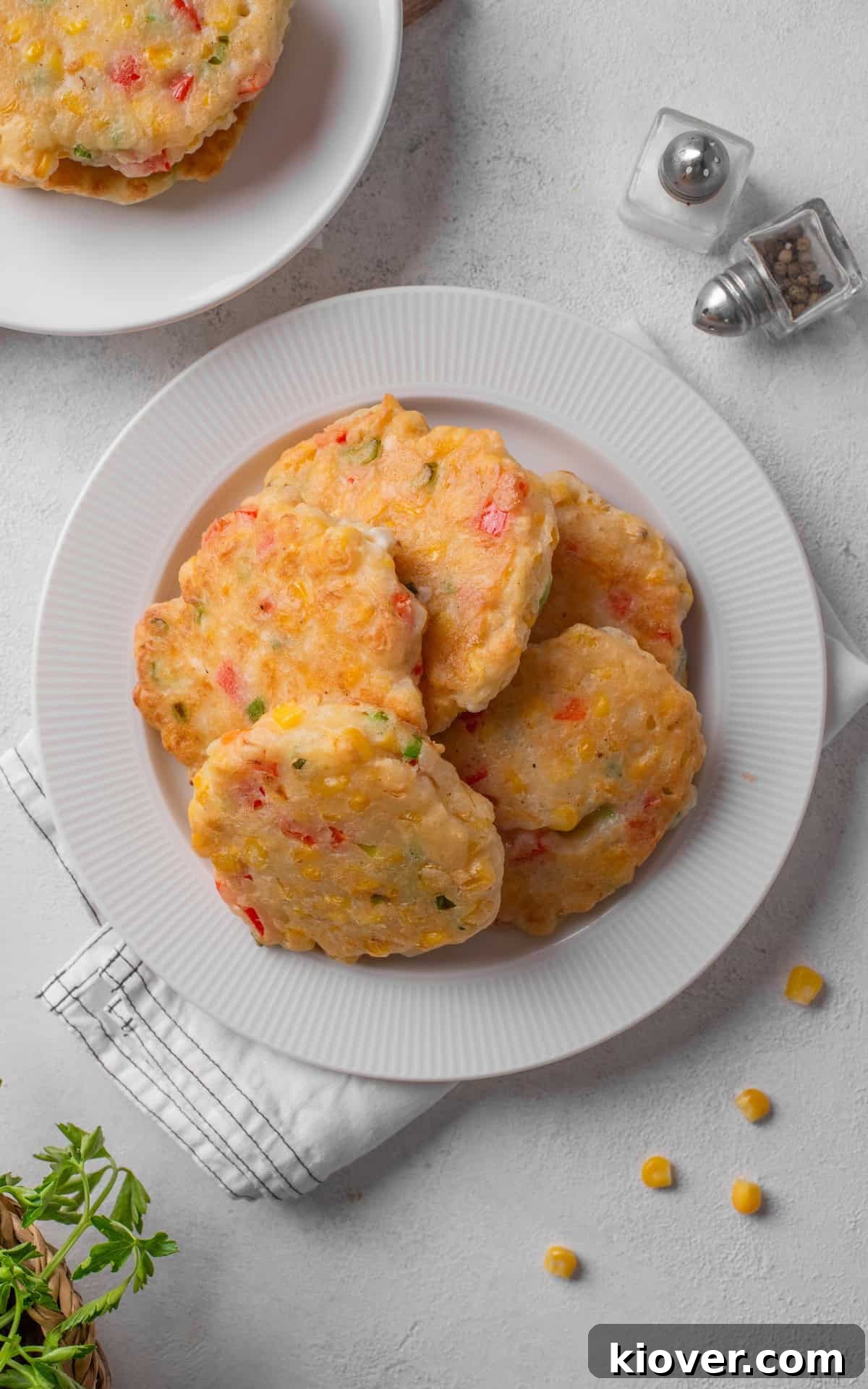 A beautifully presented plate of sweetcorn fritters, garnished with fresh herbs and a dipping sauce, highlighting their golden brown exterior.