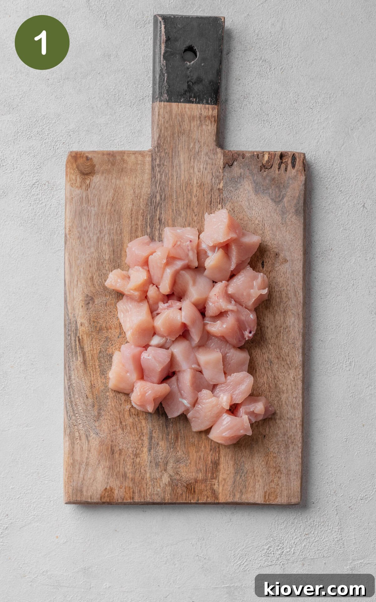 Raw chicken breasts on a wooden cutting board, ready for preparation.