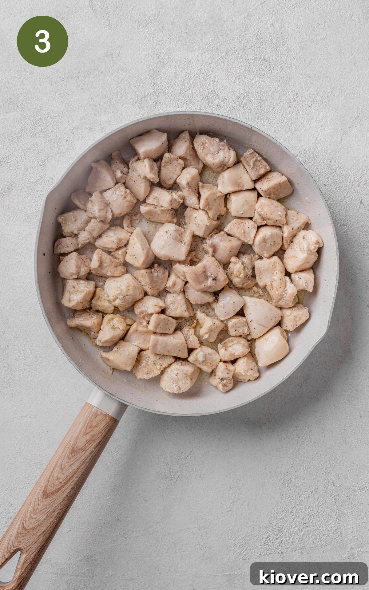 Chicken pieces being cooked in olive oil in a large skillet until golden brown.
