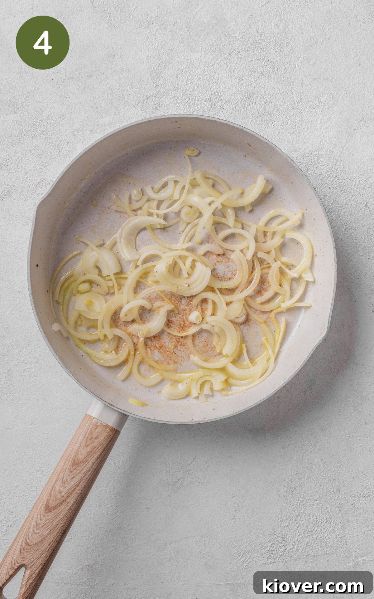 Onions and garlic being sautéed in a skillet until translucent and fragrant.