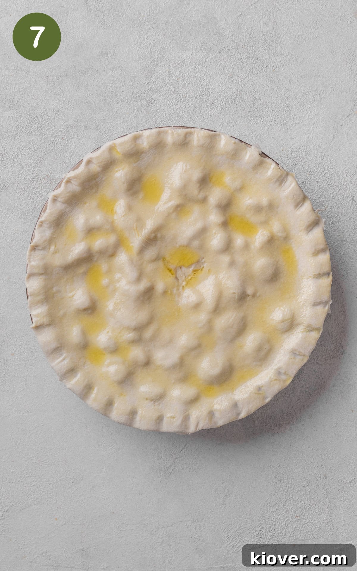 A chicken and mushroom pie in a pie dish, topped with puff pastry, before baking.