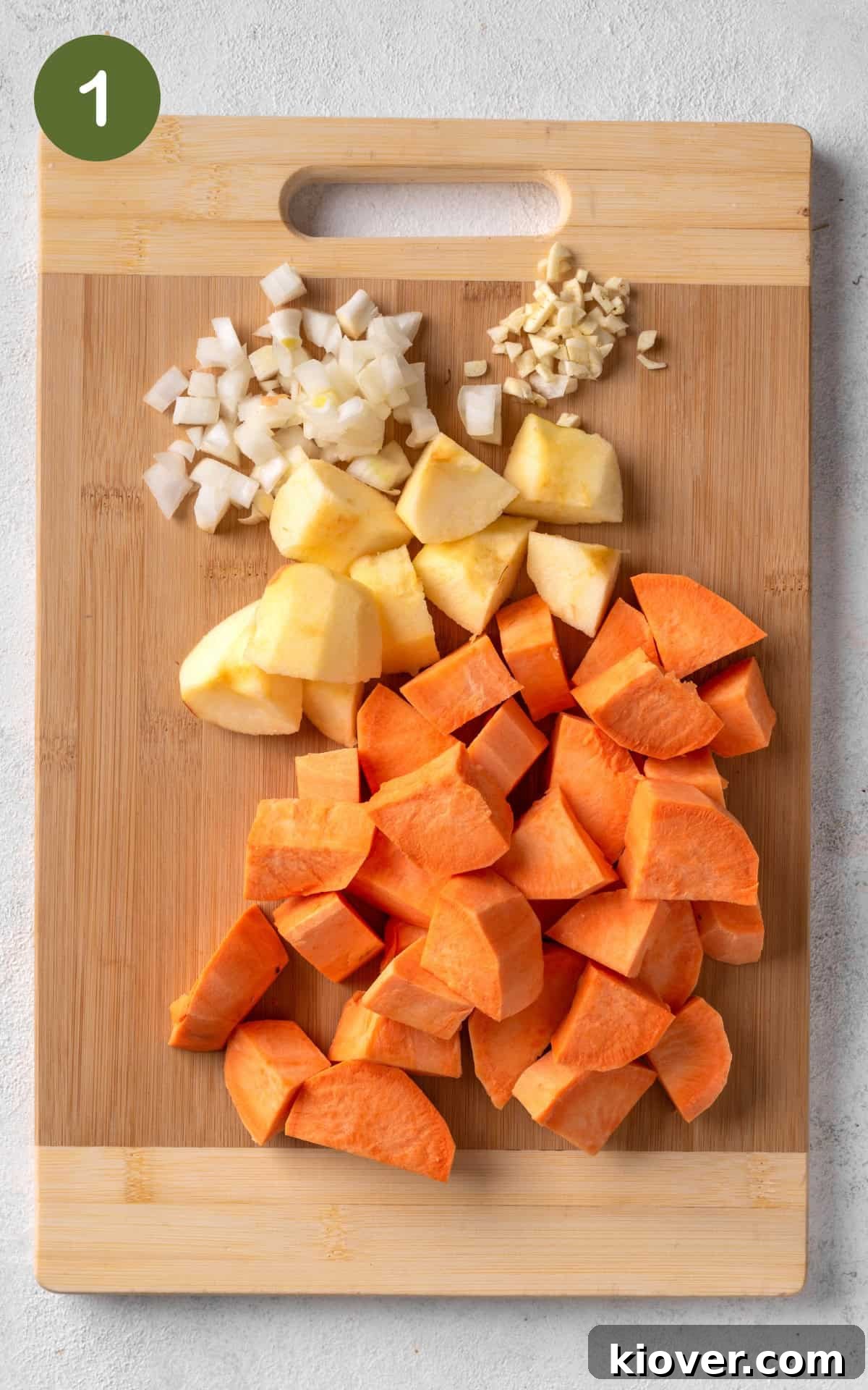Spiced Sweet Potato Warmth 4 Sweet potatoes, an apple, onion, and garlic prepared on a cutting board, ready for cooking.