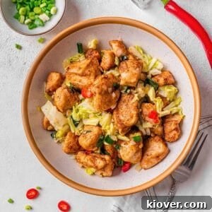 Crispy salt and pepper chicken stir-fry with vibrant vegetables, garnished with fresh spring onions.